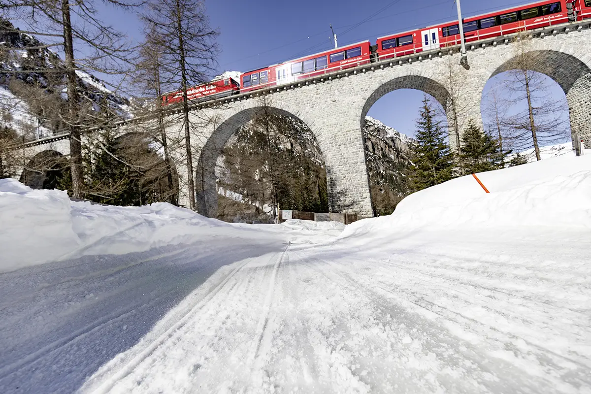 Rhätische Bahn fährt über Viadukt, unten geht die Schlittenbahn Preda–Bergün durch